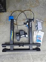 Full view of trainer frame, resistance roller, remote cable, hardware bag, paperwork