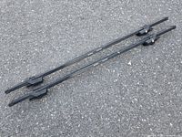 Two 52" SportRack Frontier crossbars laid on pavement