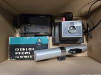 Box view showing folding camera, Polaroid Zip camera, Tower bellows box, flash gun