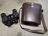 Binoculars and closed brown leather case side by side