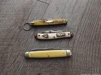 Three pocket knives closed on wood surface