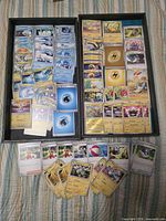Two trays filled with assorted Pokémon cards plus additional cards laid out
