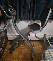 Full side view of folding exercise bike showing seat, backrest, pedals and monitor