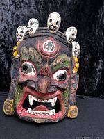 Front view of carved wood Bhairav mask showing facial details and skull crown