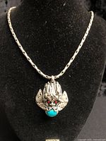 Dragon-head pendant on necklace displaying turquoise cabochon and red eyes