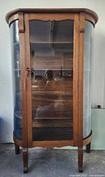 Full view of oak display cabinet front showing curved glass sides and glass door
