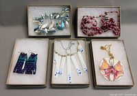 Overhead view of five boxes showing four necklaces and three earring pairs