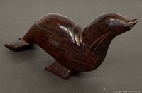 Left front view of dark brown ironwood sea lion sculpture showing incised details