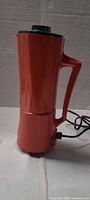 Side view of orange Waring drink mixer with handle and power cord