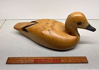 Side view of full wooden duck decoy with ruler for scale