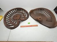 Top view of both cast iron tractor seats with ruler for scale, showing stamped 79 and crack