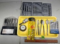 Overview of all drill bit sets, loose spade bits, arbor, wire brush and yellow tube on tray