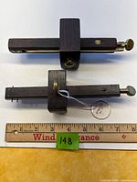 Top and side views of two ebony and brass mortise gauges beside ruler for scale