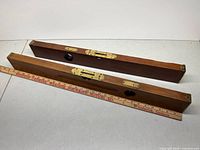 Two wooden Stanley spirit levels with brass fittings beside a yardstick for scale