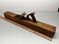 Full view of wooden bench plane with ruler showing 25-inch length