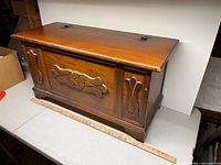Full view of wooden chest closed showing carved front and finish