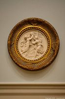 Front view of round plaque on wall showing relief and frame