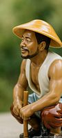 Front left view of ceramic fisherman figurine showing facial details, hat and staff
