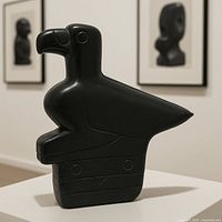 Front three-quarter view of dark soapstone bird sculpture on pedestal