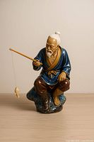 Full view of porcelain fisherman figurine on rock