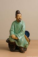 Front view of seated scholar figurine showing overall form, colors, and accessories