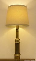 full view of brass column lamp lit with shade