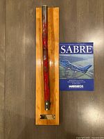 Handle mounted on wood board beside Sabre book