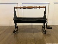 Full front view of cast iron newspaper log roller showing wood handle and crank