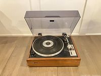 Turntable with dust cover open, platter, tonearm and control panel visible