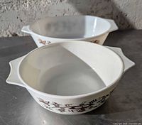 Both Pyrex England handled casserole bowls showing interior and pattern