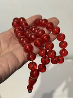 Hand holding cherry red beaded necklace showing overall strand
