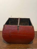 Front view of red wooden rice bucket showing curved sides and metal corner braces
