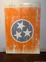 Front of orange poster board with tri-star emblem