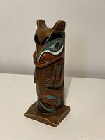Front three-quarter view of resin totem showing colour and carved details
