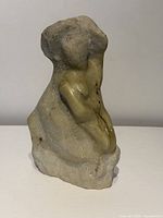 Front view of stone sculpture showing abstract female form