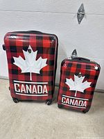 Front view of both Heys plaid suitcases showing maple leaf graphics