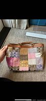 Front view of Coach patchwork tote showing multicolour panels, tan leather trim and straps