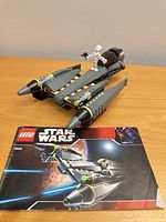 Starfighter, minifigure standing on model, instruction manual in foreground