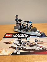 Assembled speeder with four minifigures and instruction booklet on tabletop