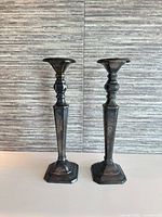 Front view of two matching metal candlesticks on light surface