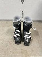 Front view of pair of black Nordica junior ski boots with four white buckles each