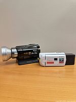 White and black Sony Handycam camcorders with docking station on table