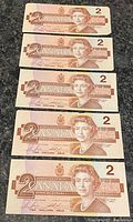 Fronts of five $2 notes showing Queen Elizabeth II portrait and denomination.