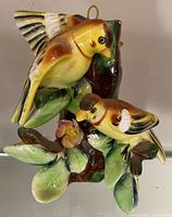 Full view of ceramic wall hanging showing two birds, leaves, flower, hanging loop