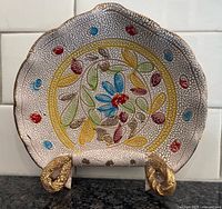 Front view of dish showing floral motif and pebble lava texture