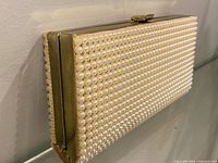 Side view showing full faux pearl exterior and gold-tone frame