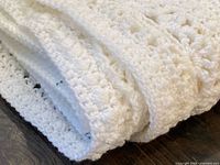 Folded white crochet blanket showing texture