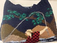 Folded navy sweater showing fly fisherman motif