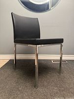 Side view of black faux leather chair with chrome legs