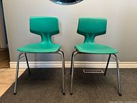 Front view of both teal plastic chairs side by side
